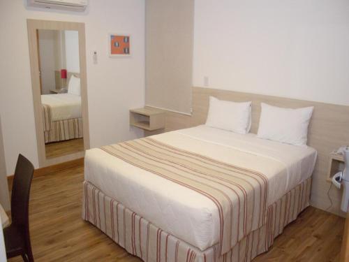 坎普斯戈伊塔卡济斯Hotel Rede 1的一间卧室配有一张带白色床单的大床