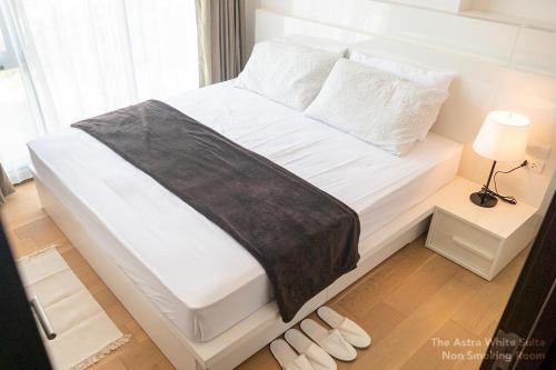 清迈Astra White Suite 13的一张带黑色毯子和白色枕头的白色床