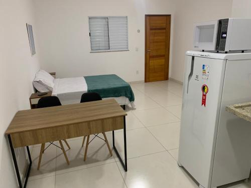 大伊瓜巴Loft PARIS para Casais, em Iguaba Grande, 150 metros da praia的客房设有冰箱、桌子和床。