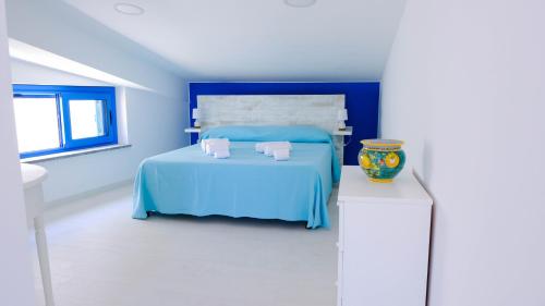 卡普多兰多Villa dei Due Ulivi的一间蓝色的卧室,配有一张床和一张桌子上的花瓶