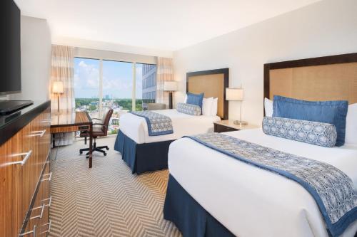 坦帕坦帕西海岸翠贡精选酒店的酒店客房设有两张床、一张桌子和一台电视。
