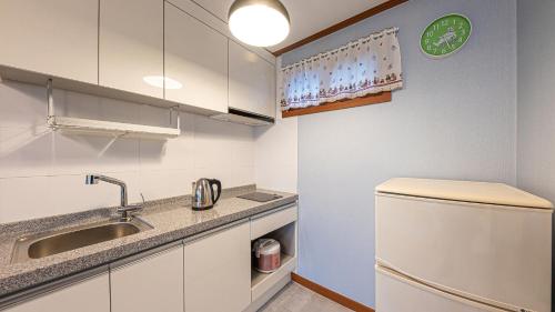 江陵市Eungabi Pension的小厨房配有白色橱柜和水槽