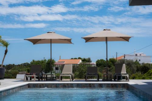 法鲁Ria Formosa Guest House的游泳池旁带遮阳伞和椅子的游泳池
