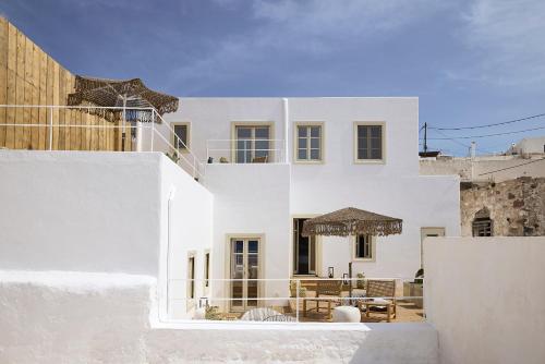 普拉卡米洛斯Niove Suites Milos的白色的房子,配有桌子和椅子