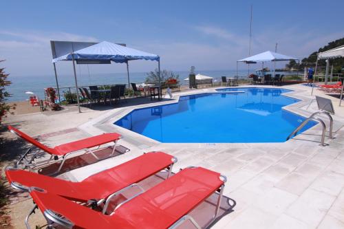 格利法达Corfu Glyfada Menigos Resort Home 72的游泳池设有2把红色躺椅