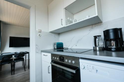 霍尔斯泰因地区诺伊斯塔特Geräumige 2-Zimmer-Wohnung的厨房配有白色橱柜和炉灶烤箱。