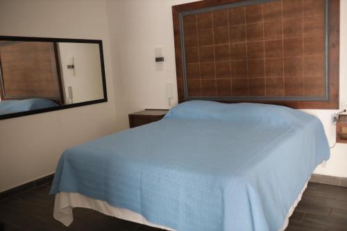 TamazunchaleHotel Posada Huasteca的一间卧室配有蓝色的床和镜子