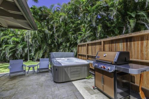KilaueaHale Nanea home的后院庭院设有烧烤设施、椅子和树木