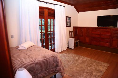 坎波斯杜若尔当Pousada Miraflores的一间卧室设有一张床、一台电视和一个窗口。