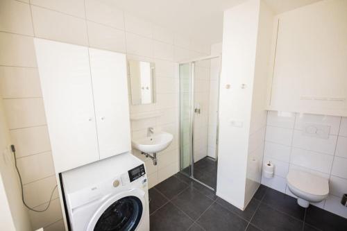 埃因霍温Elegant 2 Bedroom Apartment - 75m2的白色的浴室设有洗衣机和水槽。