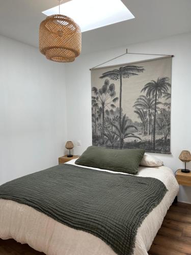 拉卡诺Le p'tit canaulais - Logement entier - rez de jardin - paisible的卧室配有一张大床,墙上挂有绘画作品