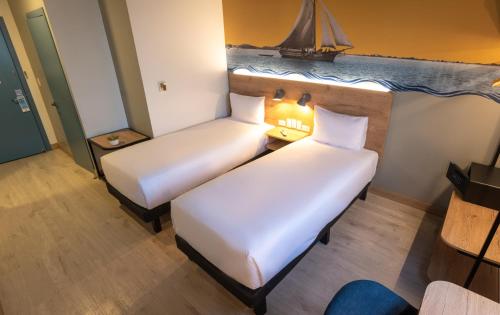 瓜亚基尔Ibis Styles El Malecon Guayaquil的墙上有帆船的房间里,有两张床