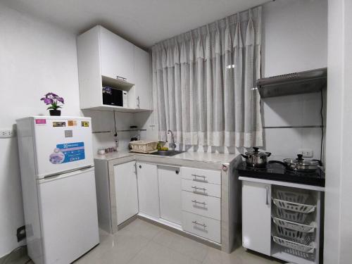 钦博特Departamento en Chimbote con cochera的小厨房配有白色橱柜和冰箱。