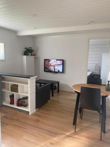 萨伦Mysig källarlägenhet i Lindvallen的客厅配有桌子,墙上配有电视