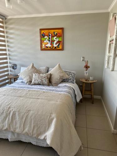拉塞雷纳Descanso y Relajo Deluxe en La Serena的卧室配有一张床,墙上挂有绘画作品