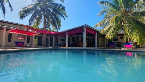 贝岛Villa Les Cocotiers的棕榈树屋前的大型游泳池