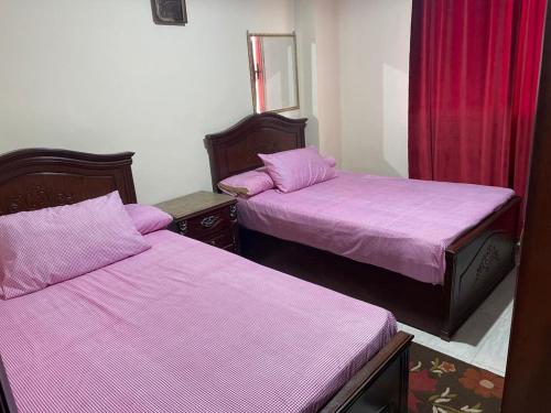 艾因苏赫纳Chalet at Lasirena Mini Egypt Resort Ein Elsokhna Families Only的紫色床单的客房内的两张床