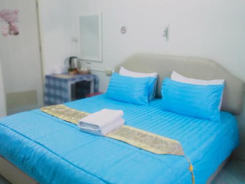 班佩幸福家园旅馆的一张蓝色的床,上面有蓝色的枕头和托盘