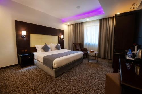 Al Buhrahفندق الرؤية محافظة الداير بني مالك的酒店客房,配有一张床和紫色灯