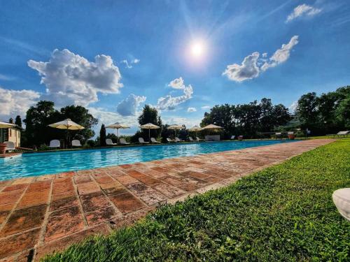 科尔托纳笆尔德立别墅酒店的一座拥有蓝天和云彩的大型游泳池
