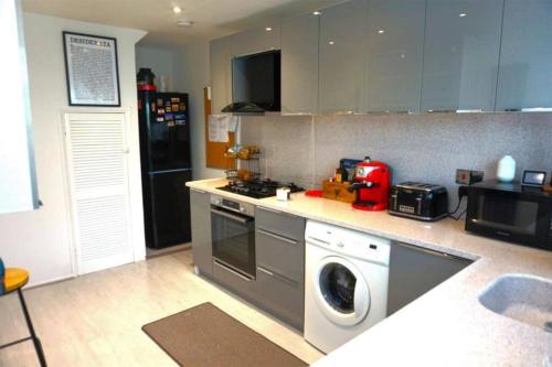 雷纳姆Lovely family home in Rainham, Kent的厨房配有炉灶和洗衣机。