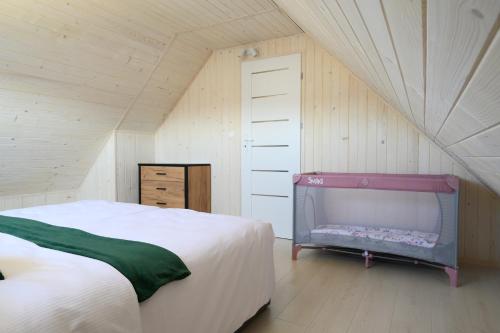 雅罗斯瓦维茨Resort Za Lasem的阁楼上的卧室配有一张床和一张婴儿床