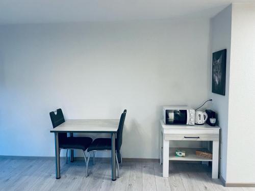 萨永Studio de vacances aux Bains de Saillon的桌子旁的桌子和椅子,带微波炉