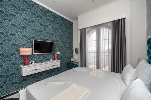 多布拉沃达Baba's Hotel & Spa的一间卧室配有一张床,墙上配有电视