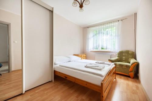 斯克拉斯卡波伦巴VacationClub – Apartament Waryńskiego 14C的卧室配有床、椅子和窗户。