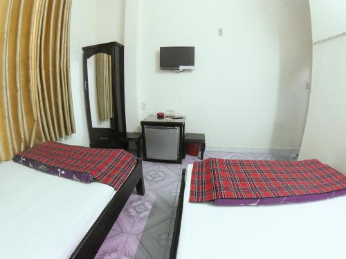 芽庄Yên Mỹ Hotel的客房设有两张床和一台墙上的电视。