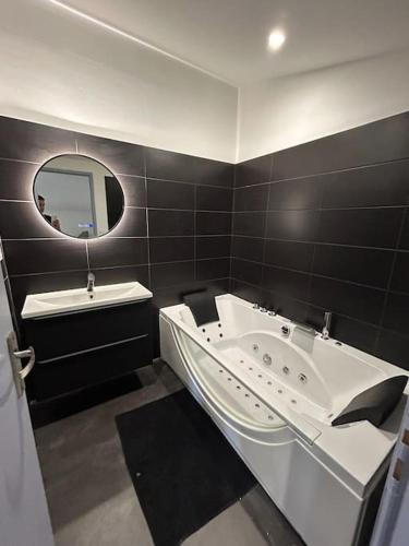 沙托盖Maison à chateaugay balneo的带浴缸、水槽和镜子的浴室