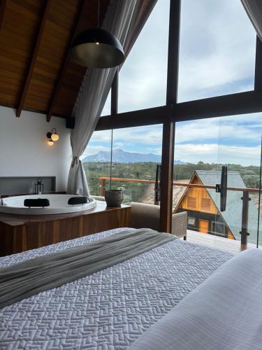 新文达移民镇Chalés Laguna Alto Viçosa的一间带浴缸、一张床和大窗户的卧室