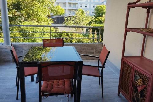 图尔Appartement 65 m² avec piscine.的阳台上配有一张黑色的桌子和椅子