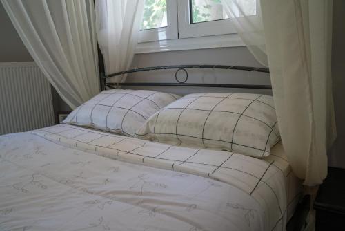 帕拉塔蒙Zak's House的一张带白色床单和枕头的床,位于窗户前