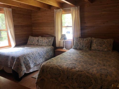 Beddington Lake Log Cabin的小木屋内一间卧室,配有两张床