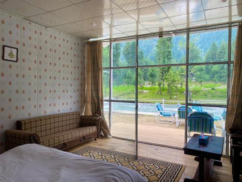 TālValhalla Resort Kumrat的一间带沙发和大窗户的卧室