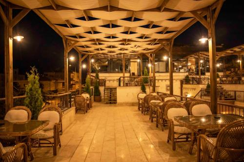 格雷梅Garden Suites Hotel Cappadocia的一间空餐厅,晚上配有桌椅