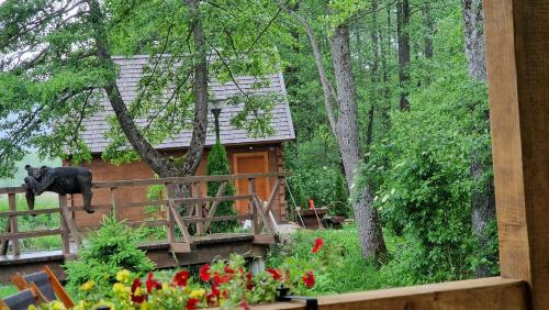 Vrelo KoreničkoVodenica Vrelo Chalets的林中的一个小屋,在栅栏上有一个黑熊