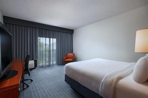 阿林顿Courtyard by Marriott Dallas Arlington Entertainment District的酒店客房配有一张床、一张书桌和一台电视。