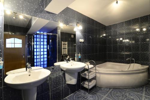 比得哥什依卡酒店的黑色瓷砖浴室设有两个盥洗盆和一个浴缸