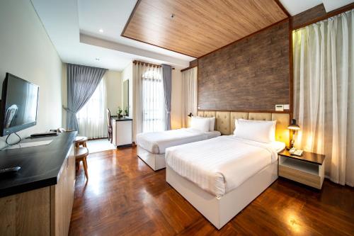 金边LCS Hotel & Apartment的酒店客房设有两张床和电视。