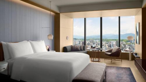 福冈The Ritz-Carlton Fukuoka的卧室设有一张白色大床和大窗户