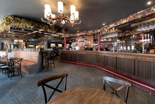 安布尔塞德Wateredge Inn- The Inn Collection Group的餐厅设有酒吧,配有桌椅