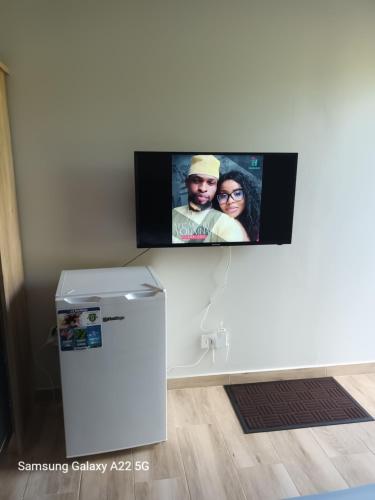 OuanganiChez Mkoudou的冰箱旁的墙上设有平面电视