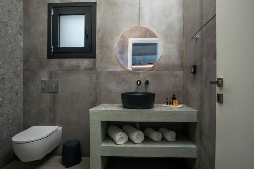 法里拉基Nόka Suite Apartments的一间带水槽、卫生间和镜子的浴室