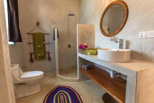 平圭Pingwe Beach Apartments的一间带水槽、卫生间和镜子的浴室