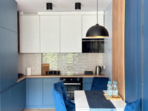 马佐夫舍地区新庄园DMK Blue Apartment near Warsaw-Modlin Airport的厨房配有蓝色橱柜和一张带蓝色椅子的桌子