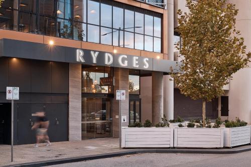 珀斯Rydges Perth Kings Square的站在建筑物前走的女人