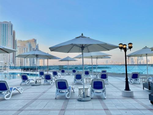 沙迦Corniche Hotel Sharjah的庭院里摆放着一组椅子和遮阳伞