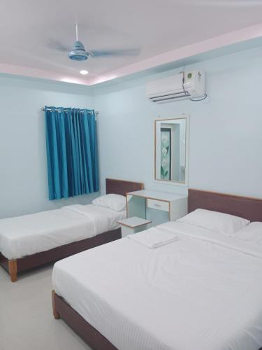 蒂鲁奇奇拉帕利KN residency, near Trichy Airport的一间卧室配有两张床和蓝色窗帘